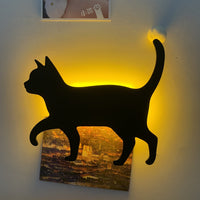 OptiLair black cat silhouette wall night light with warm yellow sound-sensor glow mounted on a bedroom wall