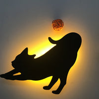 OptiLair cat-shaped acrylic wall night light with warm yellow sound-sensor glow and decorative rattan ball accent.