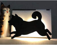 OptiLair cartoon dog silhouette night light with sound-sensor warm yellow glow on a white acrylic base