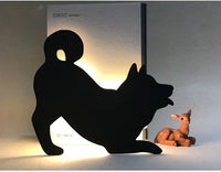 OptiLair black acrylic dog-shaped night light with warm yellow sound-sensor illumination for bedroom decor.