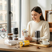 OptiLair portable wireless electric coffee grinders in white, black, and yellow on a table with a smiling woman.