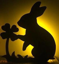 OptiLair rabbit-shaped acrylic night light with warm yellow glow and sound-sensor activation for kids bedroom decor.